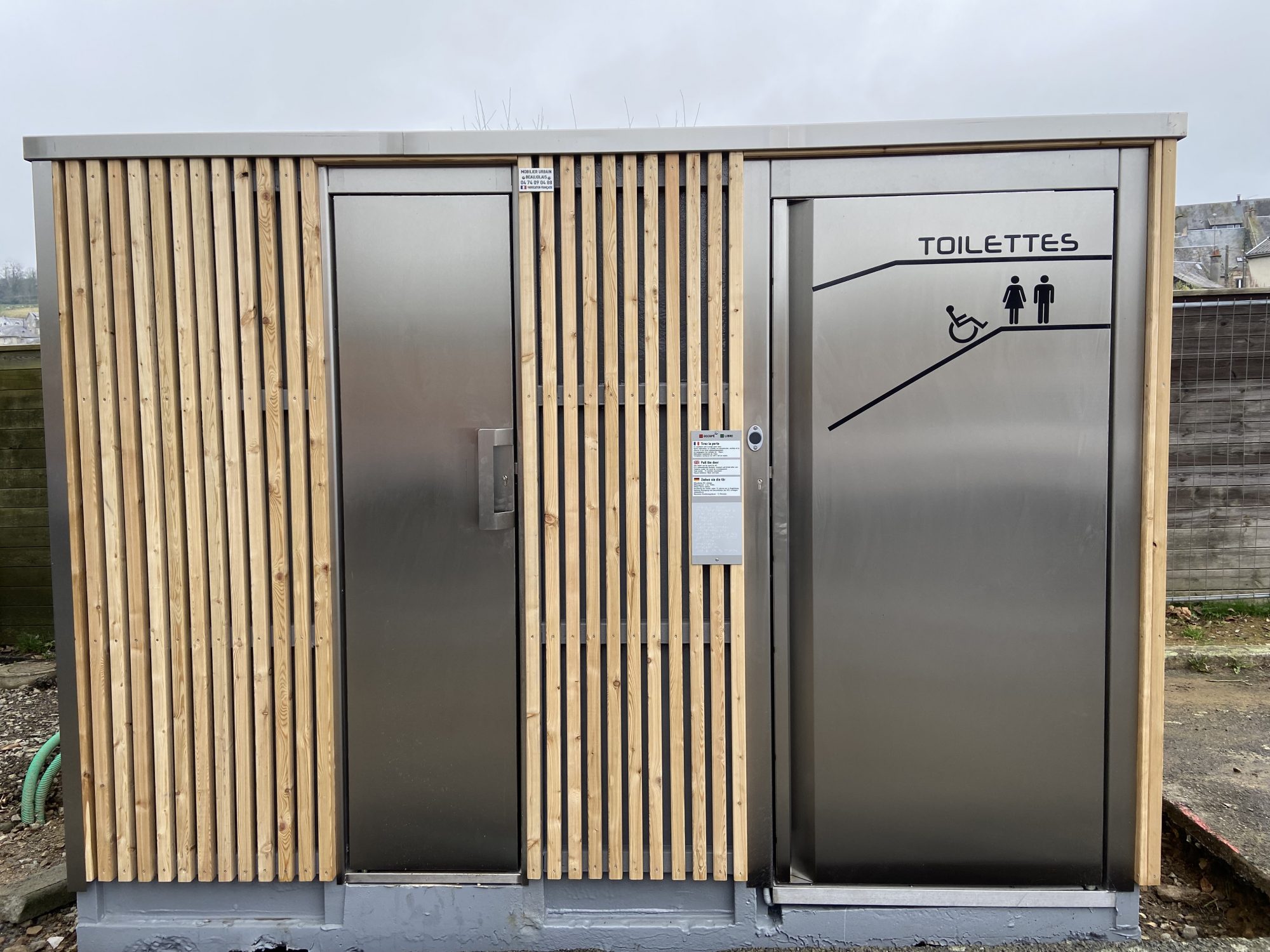 Cabine PMR avec mur urinoir, équipée de local technique, de finitions extérieures en bois, en trespa et en béton - référence 2073_2